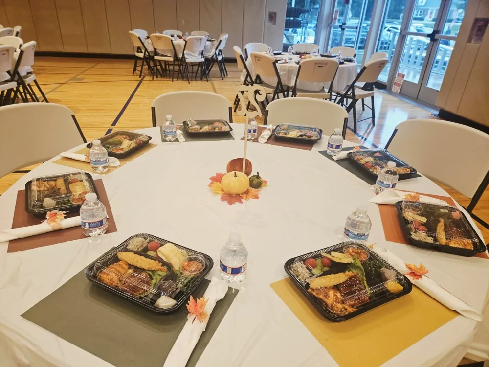 Table set with Korean lunch boxes, water bottles, and autumn leaf napkin rings for senior guests