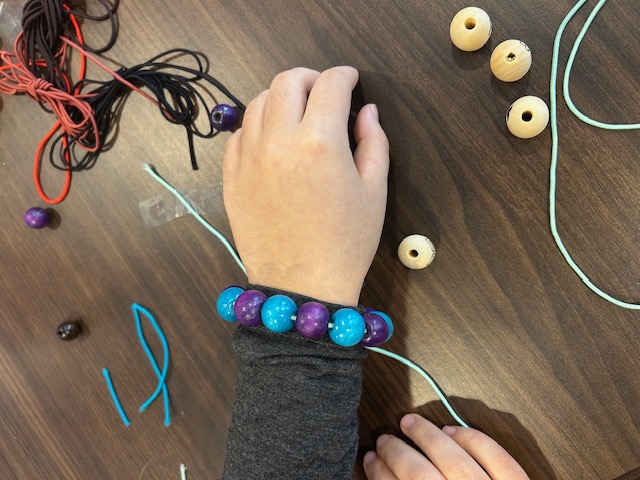 A volunteer restringing beads at the craft table