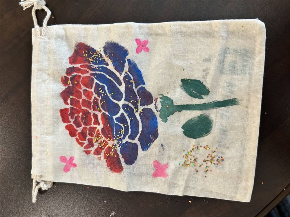 Hand-painted drawstring bag with a glittered flower design