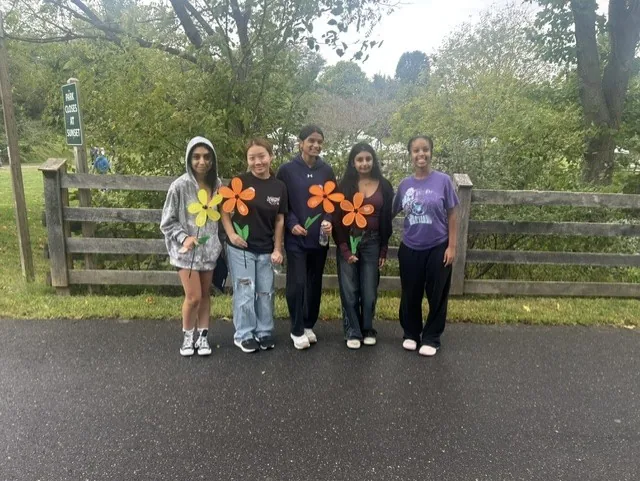 Club members holding pinwheel flowers along a fence at Centennial Park before the Walk to End Alzheimer's